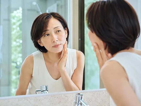 手を頬に当てシワを気にする女性