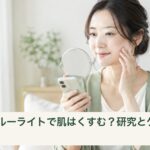 スマートフォンを手元に持ち、鏡で頬の様子を確認する女性