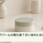 乾いた洗面台に置かれた無地のクレンジングバーム容器と清潔なスパチュラ
