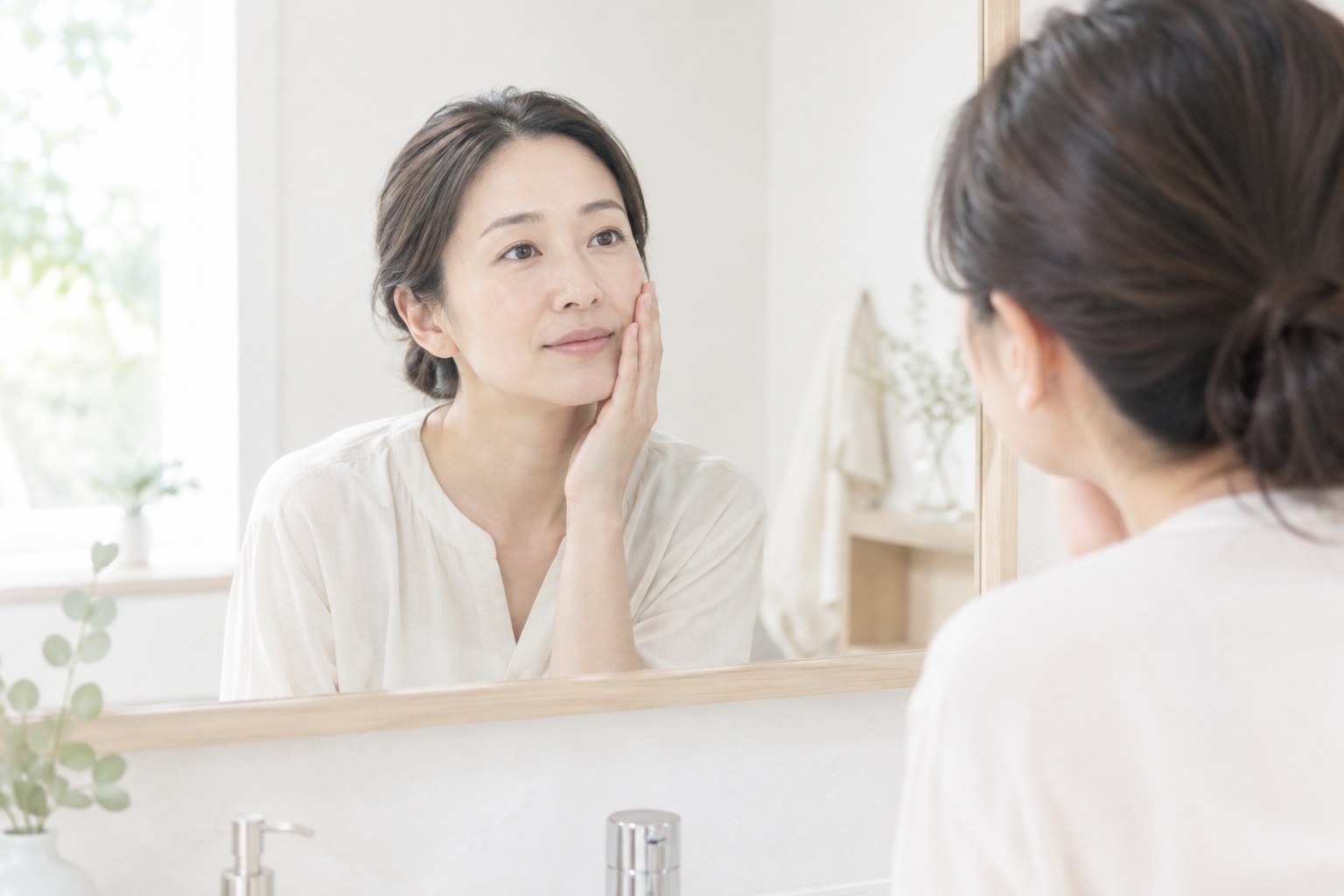 拭き取りをする前に鏡で頬の状態を確認する女性